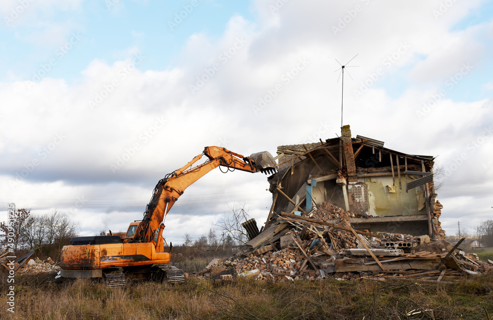 Excavator demolishing a residential house in a rural area